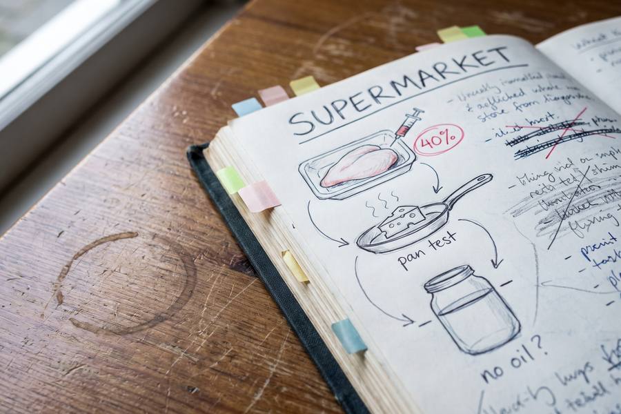 The notebook open on a page headed supermarket: a drawn chicken breast with a syringe and 40% circled, a slice of cheese in a pan, a jar of peanut butter with the oil line marked