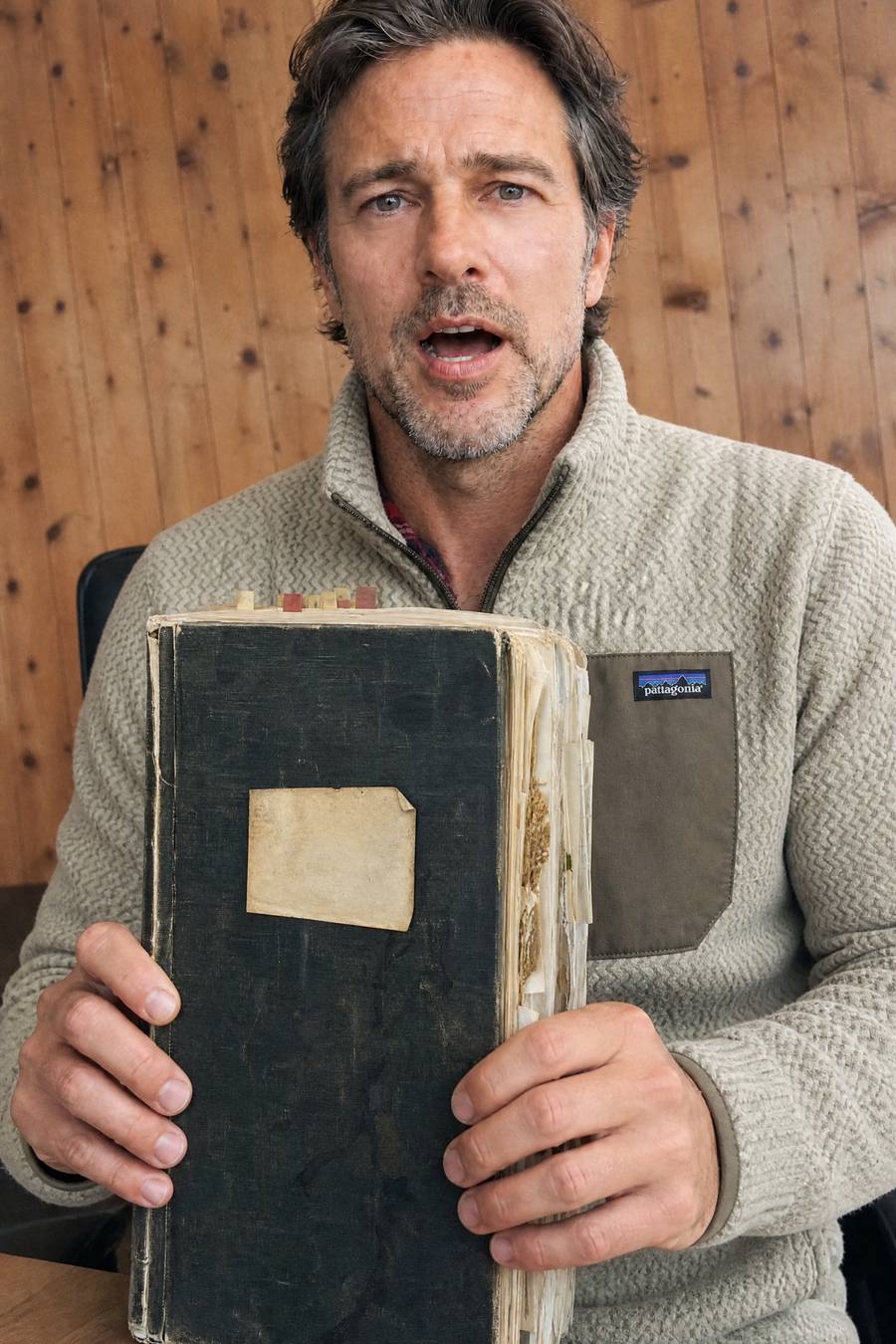 Silas Kerr holding a worn black notebook stuffed with loose pages